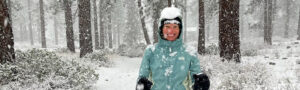 Smiling woman in the forest being covered with falling snow